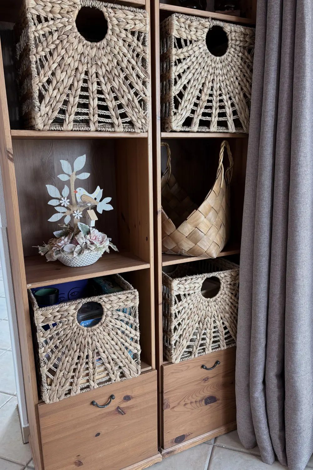 A wooden shelf unit holding woven storage baskets and a small decorative arrangement